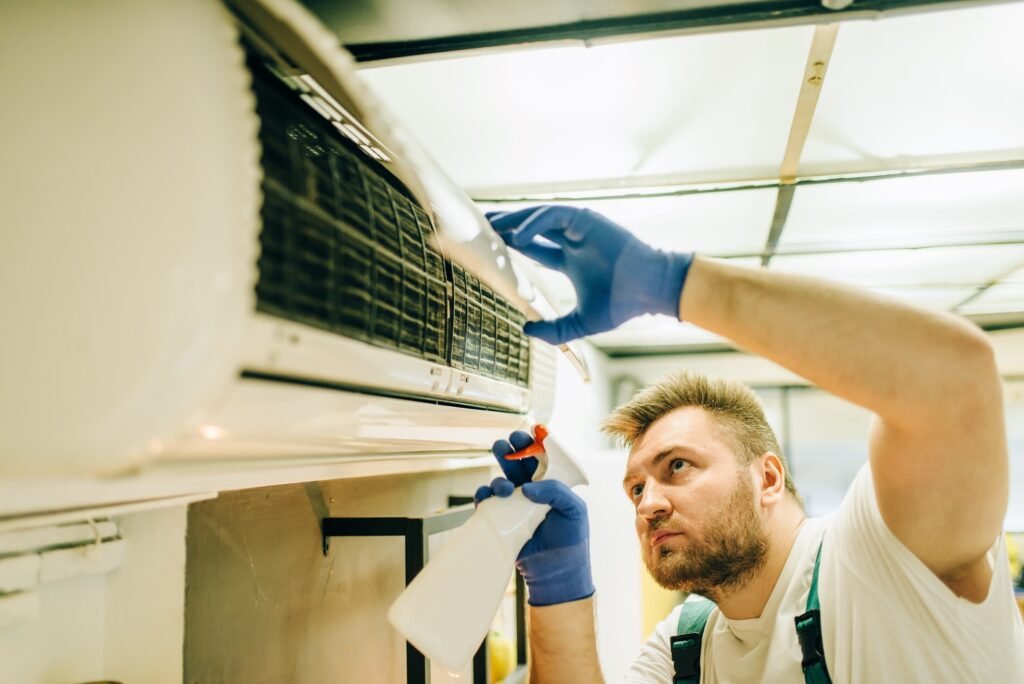 Repairman in uniform cleans the air conditioner
